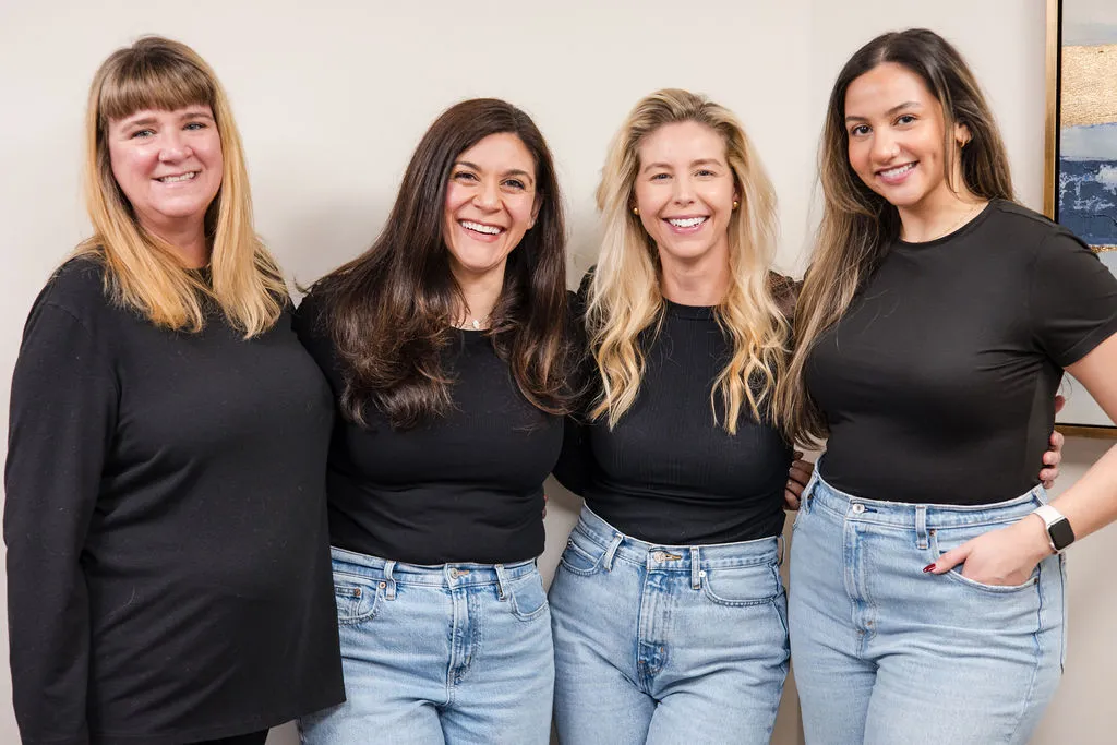 Living Well Counseling Center's four therapists standing side by side in black tops and jeans, smiling.